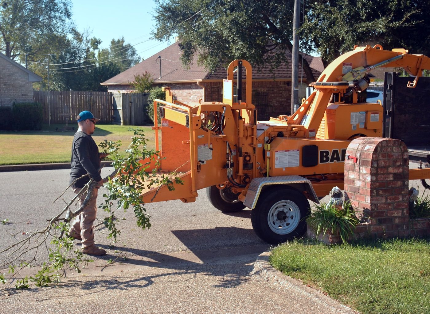 Tree-service worker feeding trimmed branches into a professional wood chipper